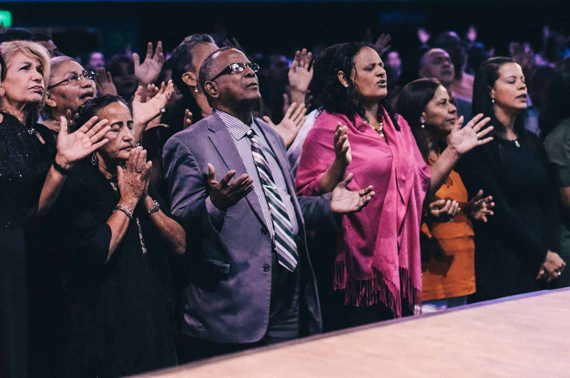 A group of people praying in a church auditorium.